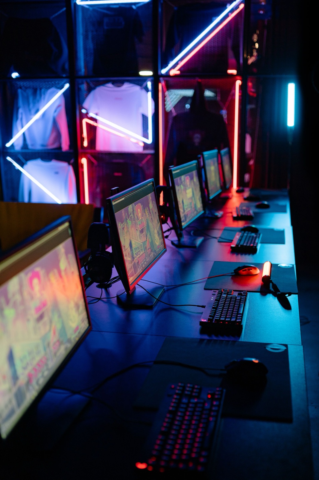 Fila di postazioni gaming free-play con luci neon, pronte per lo stand