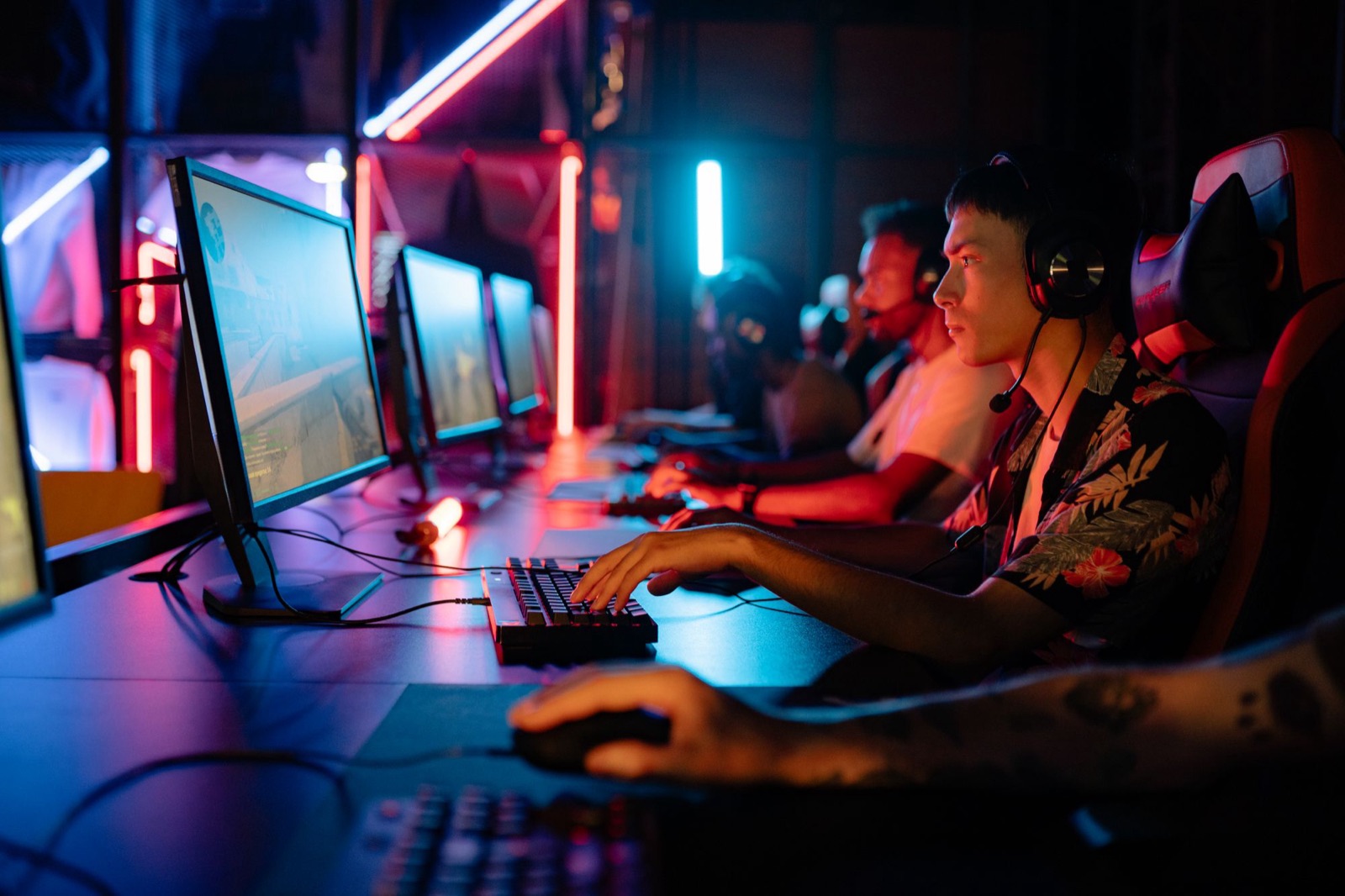 Team esports in gara ai PC di una sala LAN illuminata da luci neon